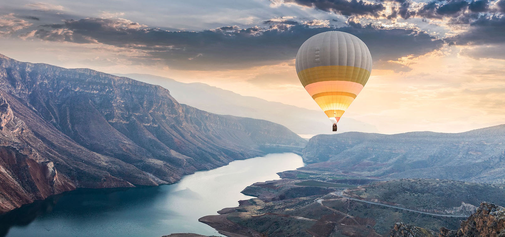 A hot air balloon floating over a canyon river